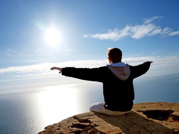 Man Sitting on Edge of Mountain